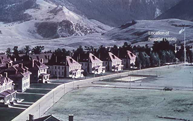 View across Fort Yellowstone, with hospital obscured by trees.