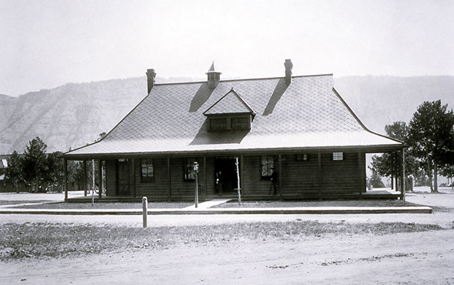 Wooden single story building with a wrap-around porch.