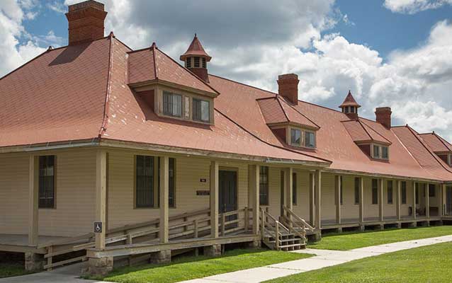 Tan wooden building with red brick chimneys and red tin roof. Tan wooden building with red brick chimneys and red tin roof.