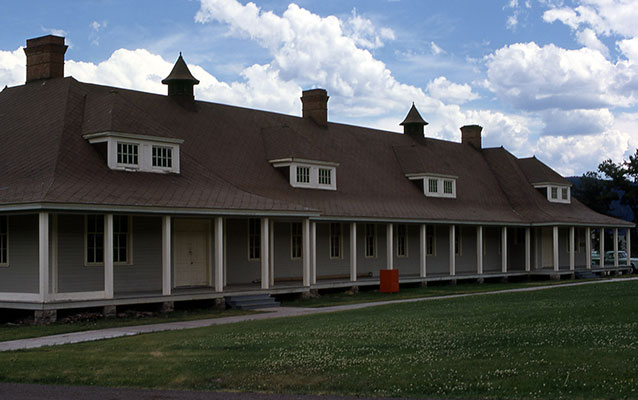 Tan wooden building with red brick chimneys and red tin roof. Tan wooden building with red brick chimneys and red tin roof.