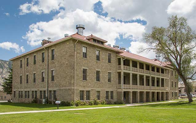Large, three-story stone building with porches on each story and red tile roof. Large, three-story stone building with porches on each story and red tile roof.