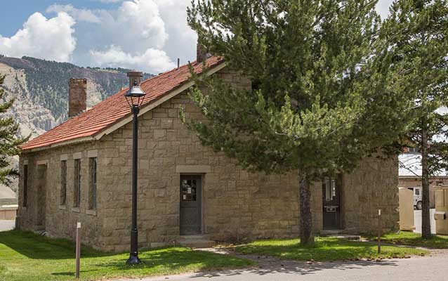 Small stone building with red tile roof and a large tree standing in front. Small stone building with red tile roof and a large tree standing in front.