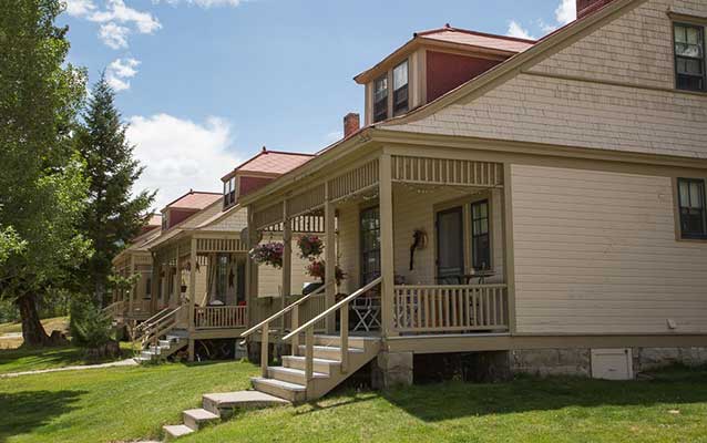 Tan, wooden, two-story home with three similar homes behind.