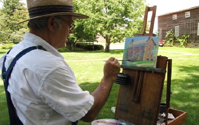 man painting outside the amana arts guild