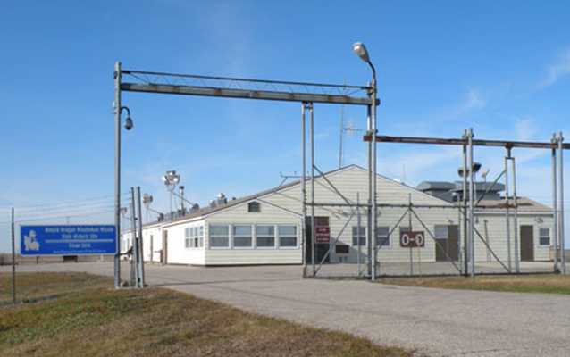 A tan building inside a fenced enclosure