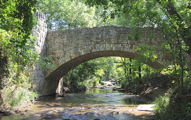 a stone bridge over a creek in the woods