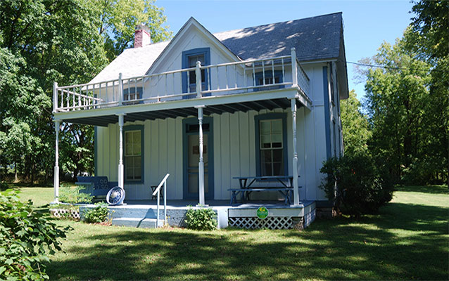 Two story Gothic Revival house faces west. The façade has a two story porch. 