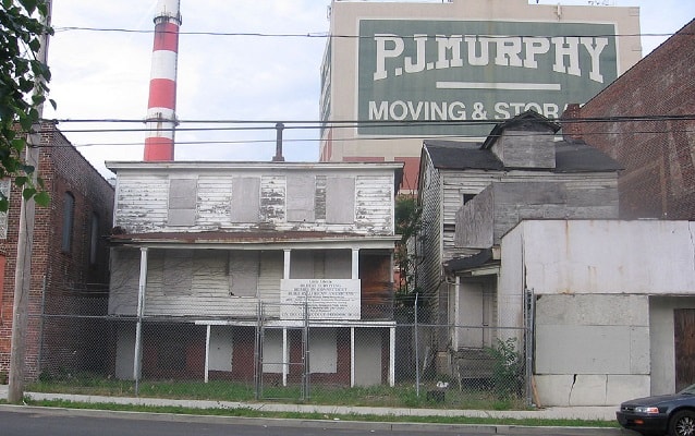 Two houses, both 3 stories high-dilapidated and boarded up.