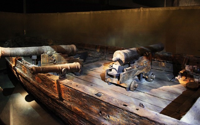 Wooden boat with two big cannons and one small one 