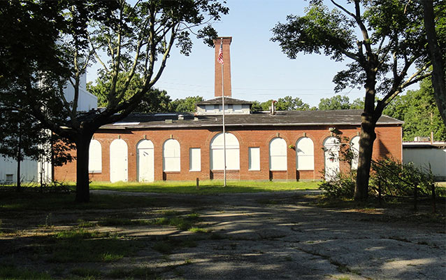 One and one half story, nine bay by nine bay brick building with a side-gabled roof. 