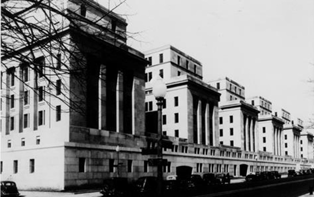 Old cars line the street in front of the Department of Interior