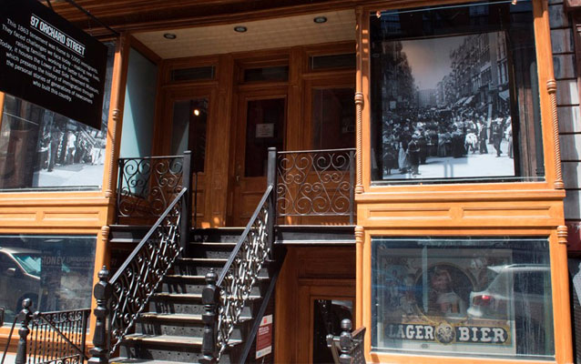 An old building front. A rod iron stair climbs to a wood trimmed porch. 