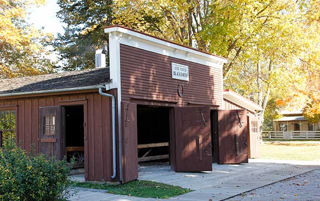 A low barn-like wood building is painted brown and has a facade with white trim. A low barn-like wood building is painted brown and has a facade with white trim.