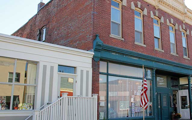 A brick commercial building has two stories and green and cream gingerbread trim. A brick commercial building has two stories and green and cream gingerbread trim.