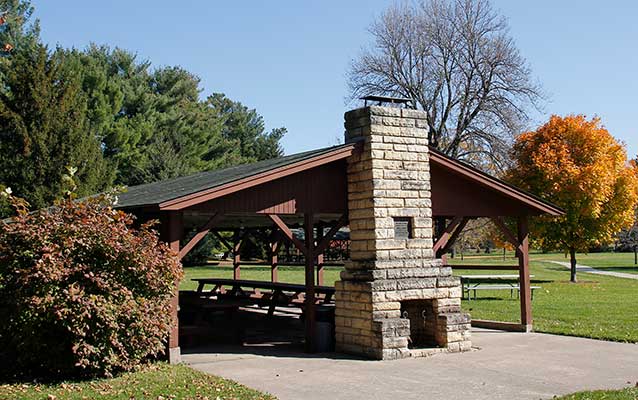 A timber picnic shelter has a limestone chimney and is painted reddish brown. A timber picnic shelter has a limestone chimney and is painted reddish brown.