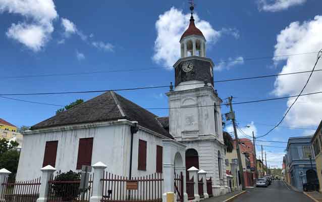 a white building with tall steeple alongside a road