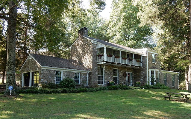 Two-story stone dwelling with a one-story garage, a two-story central core, and a one-story addition