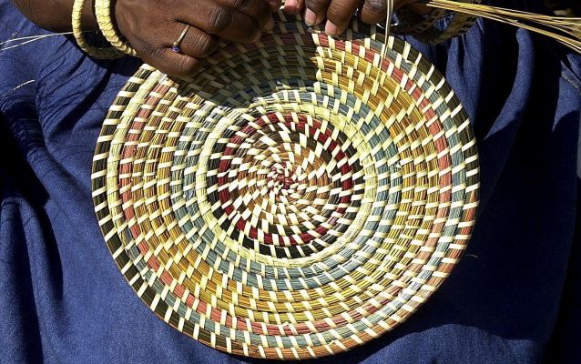 Person weaving a sweet grass basket.