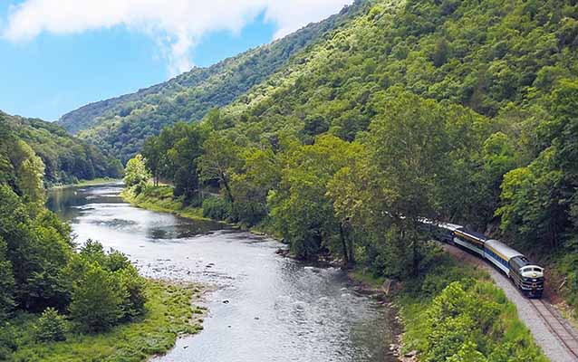 Potomac Eagle excursion train along the South Branch Potomac River in WV forest.