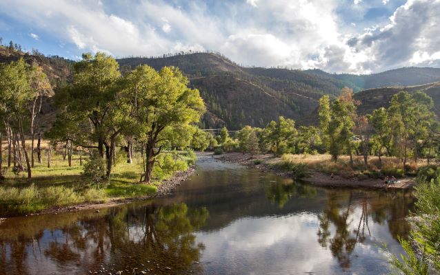 Tree lined river with mountains in the background.