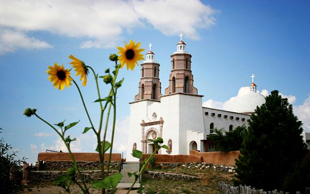 White and brown chapel with sunflowers in the foreground.