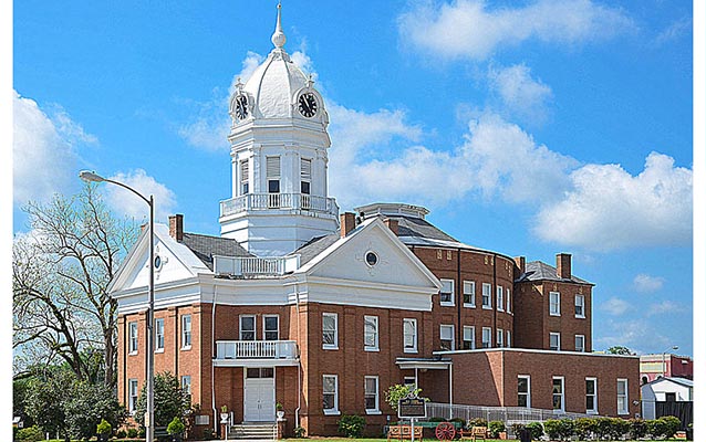 Exterior, brick courthouse with white roof and domed tower against a blue sky