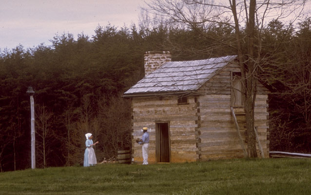 historical interpreters stand in front of a cabin