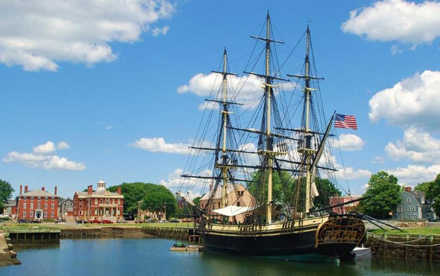 A three-masted sailing ship moored in a village of small brick buildings. A three-masted sailing ship moored in a village of small brick buildings.
