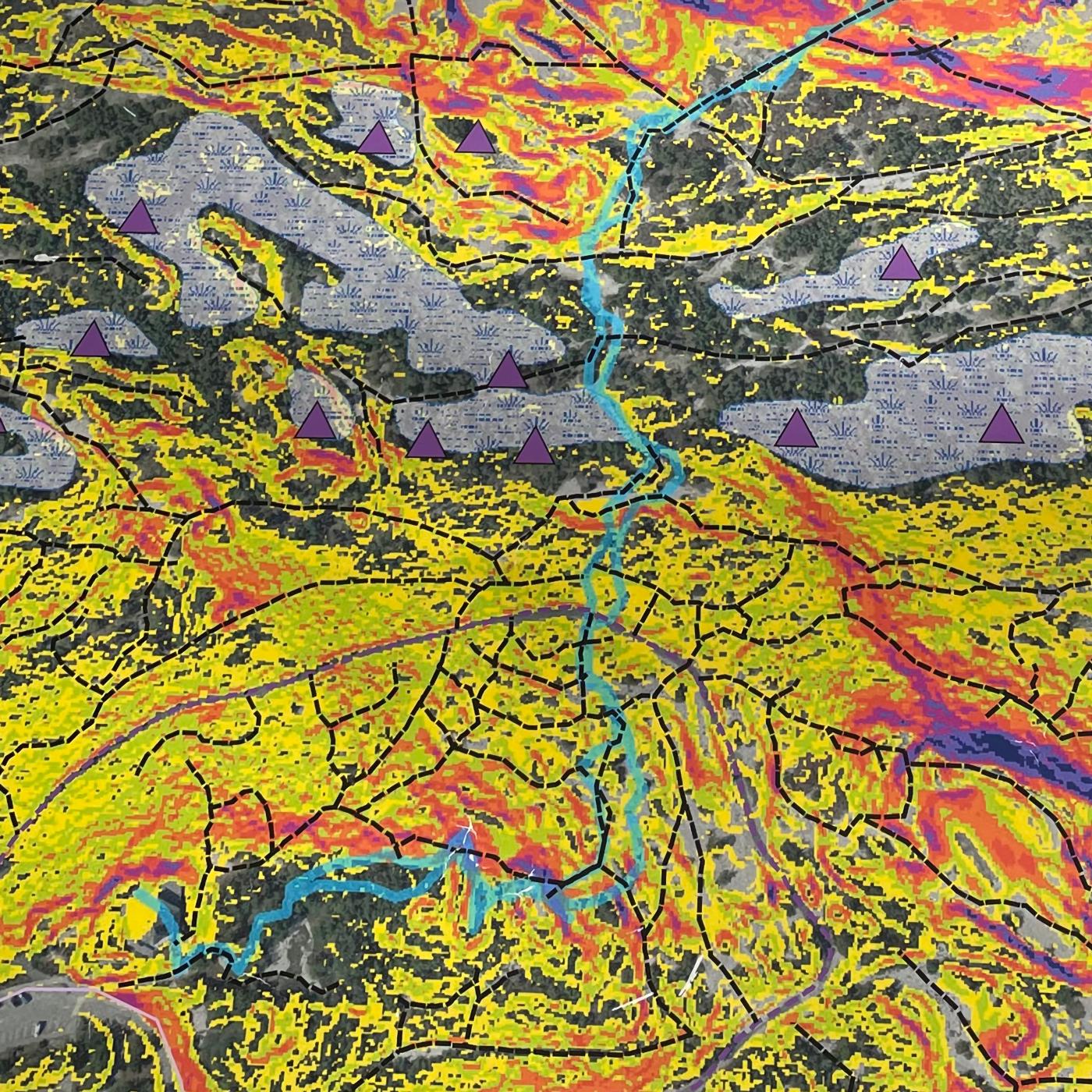Closeup of vibrant map with areas of yellow, purple triangle markers, and a light blue trail