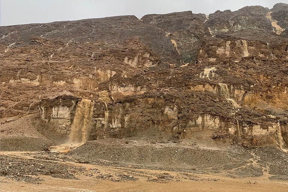 Brown mountainside with streams of waterfalls rushing down.