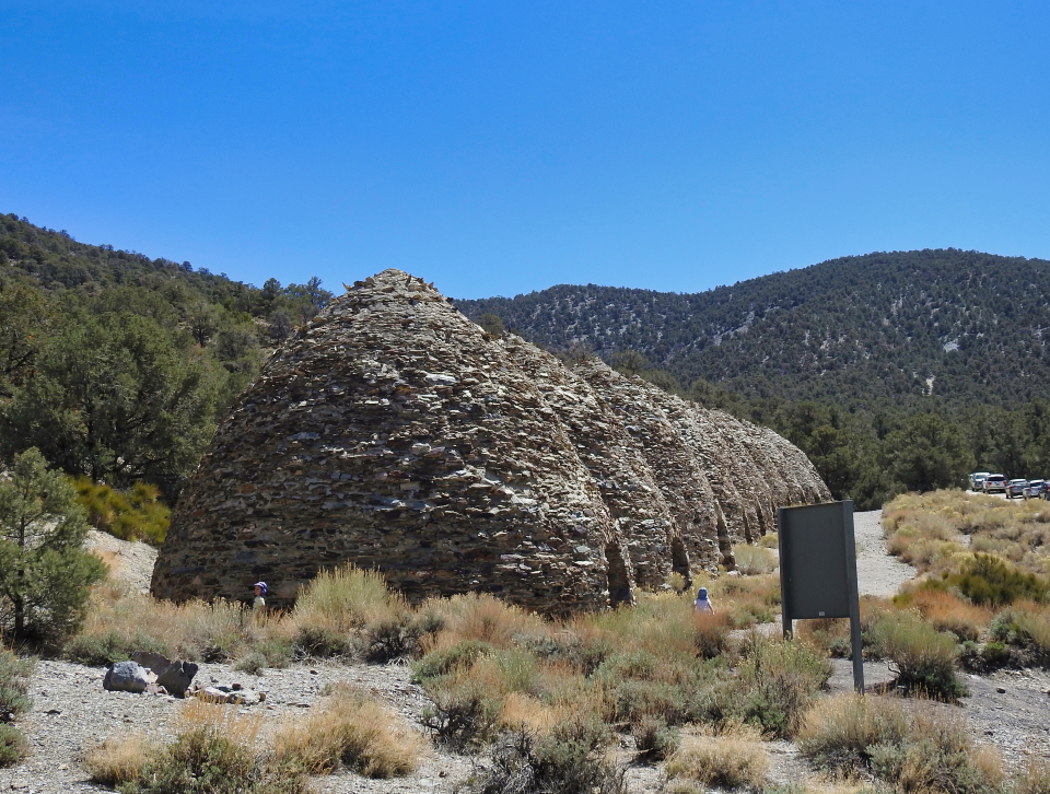Black & White photo of Conical shaped brick ovens with hills behind