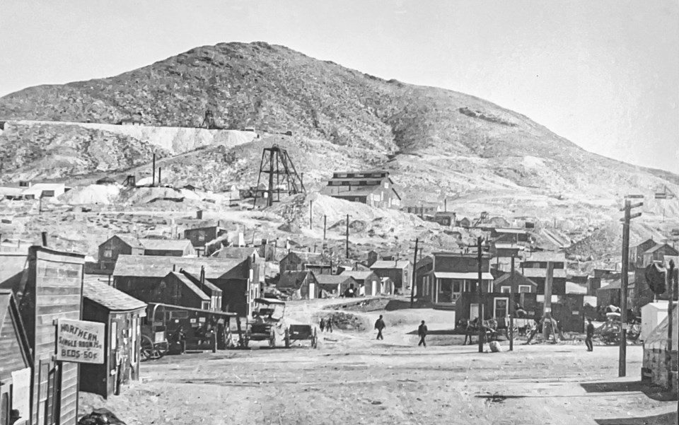 People and buildings with mountain in background.