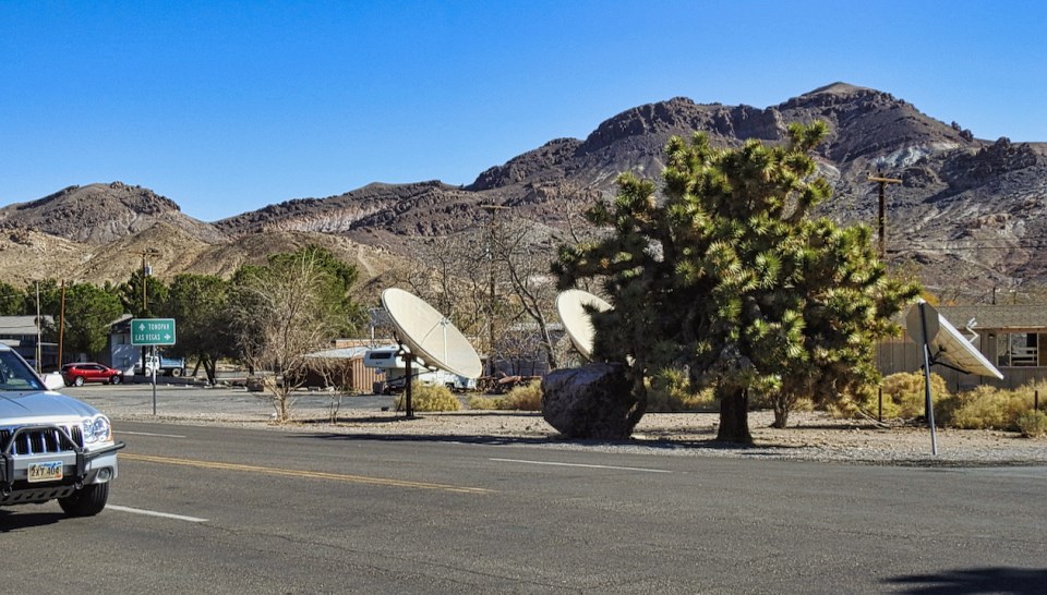 Wooden buildings, dirt street, and mountains in background.