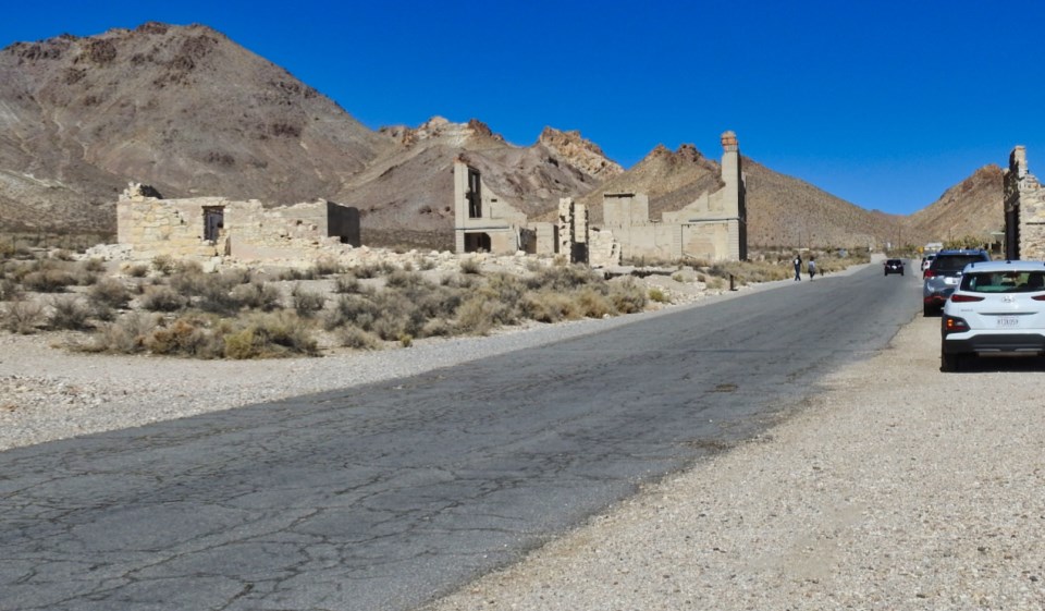 Men marching past buildings with mountains in background.