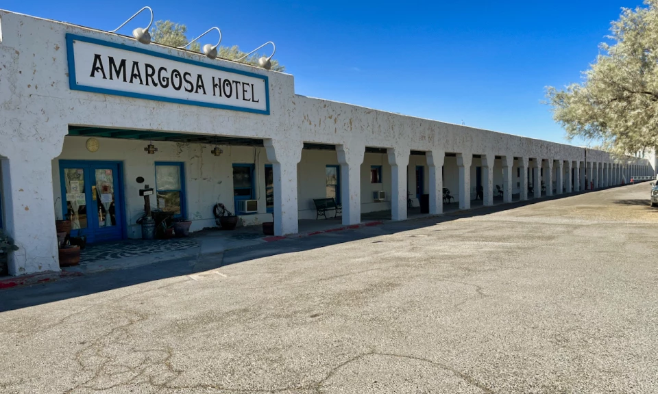 Men in front of old stucco building with car in front.