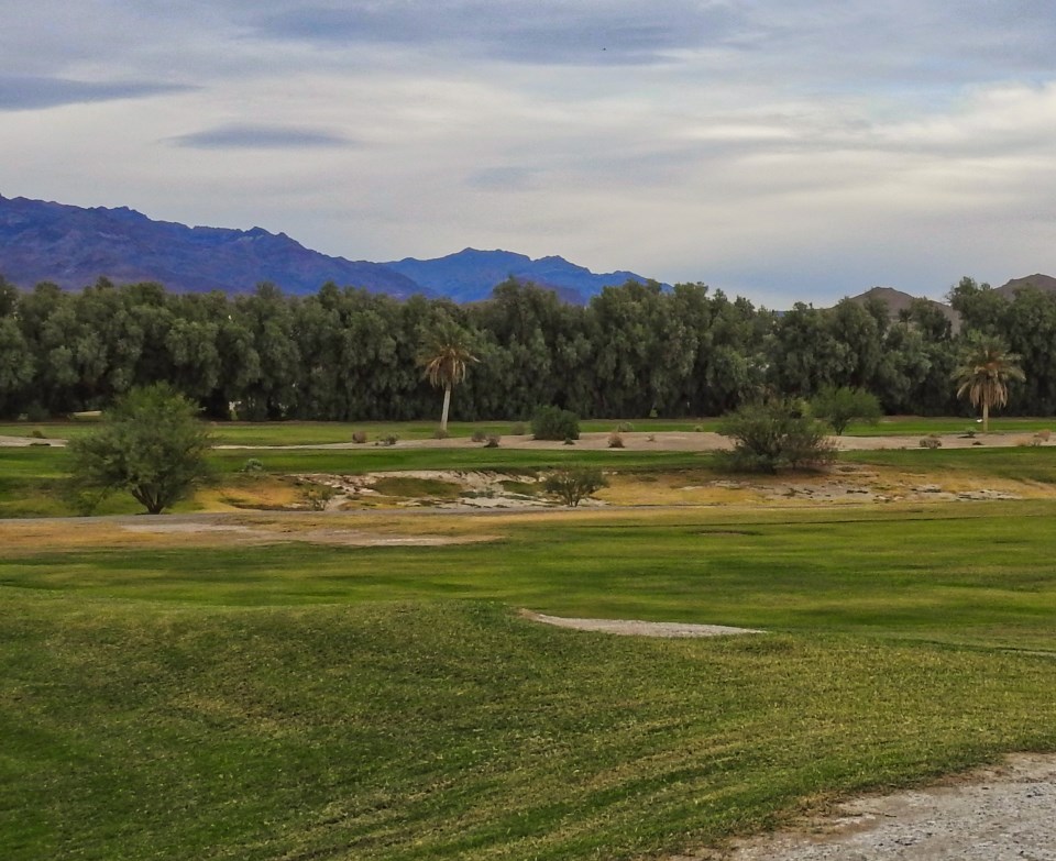 Men and women play golf with desert mountains in background