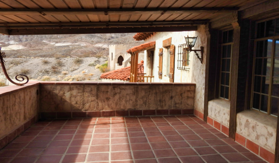 Two men and a woman on a porch next to a telescope.