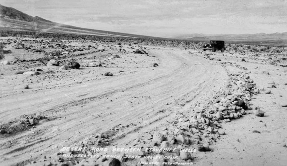 Dirt road with car in desert.