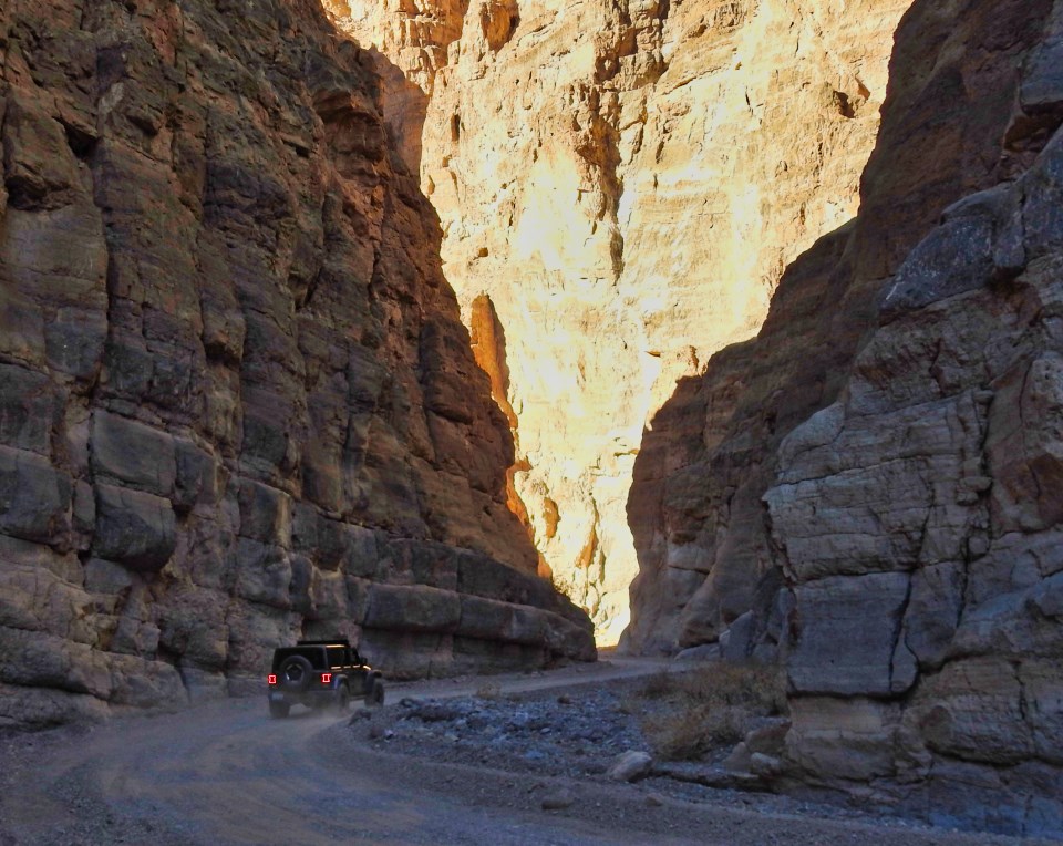 An old car driving through narrow canyon.