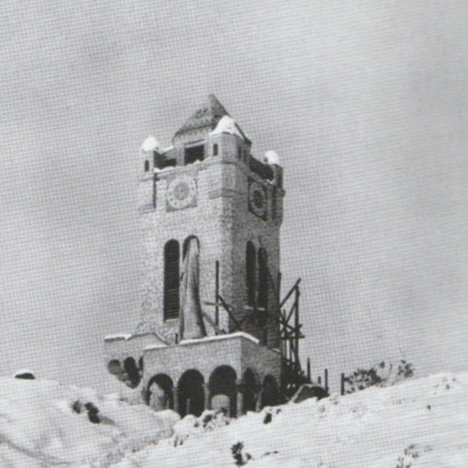 A clock tower with snow surrounding it.