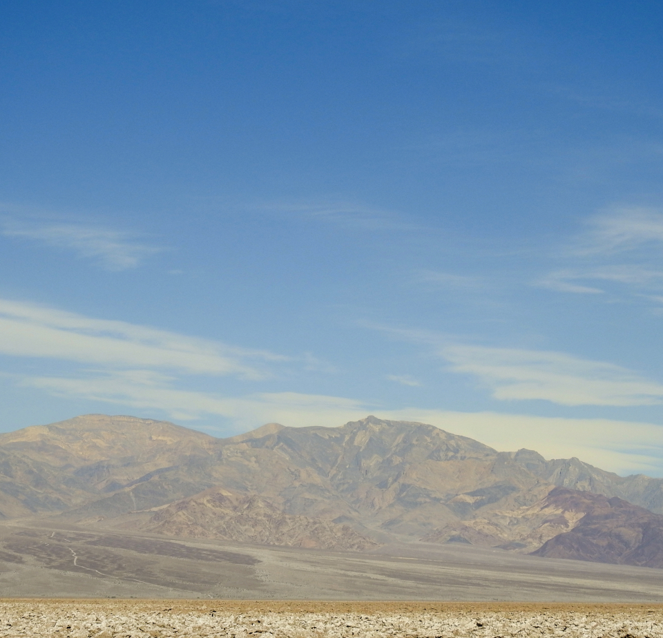 A blast of water and rock rises from flatland with mountains in background.
