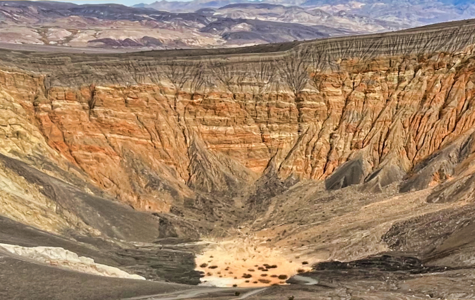 Colorized postcard of rocky crater with pool at bottom.