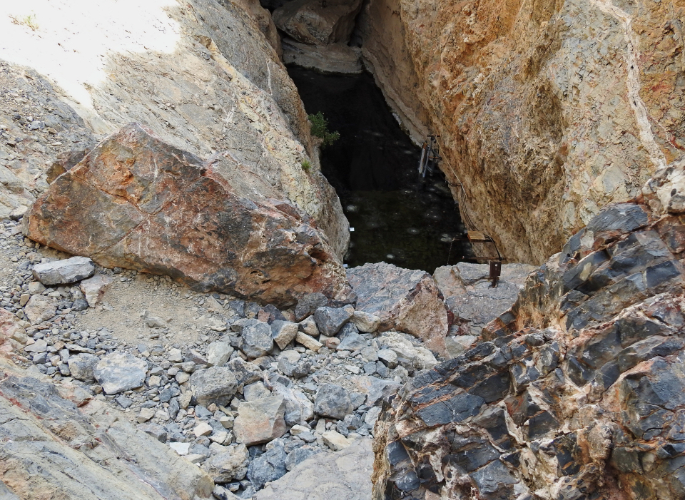 A group of people with SCUBA diving equipment in rocky pool.