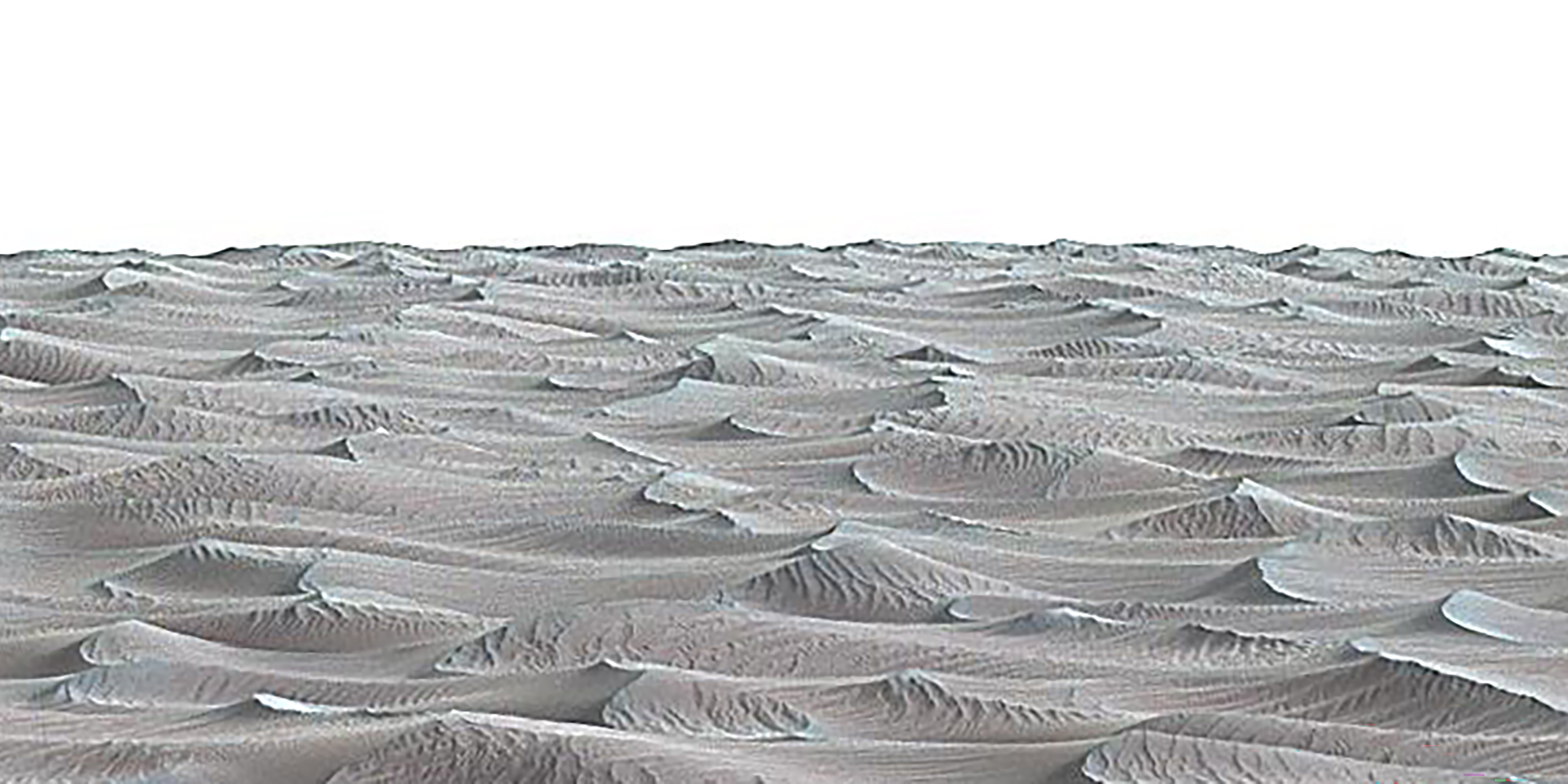 The photograph captures a sprawling landscape of sand dunes under a clear blue sky, set against a backdrop of distant mountains. It evokes a sense of calm and isolation.