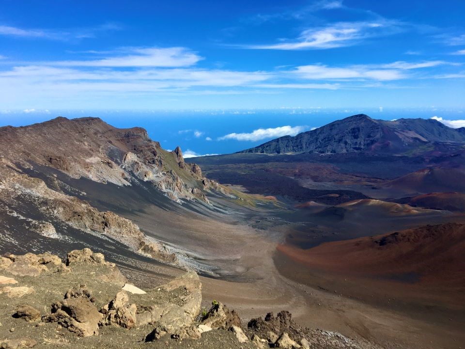 multicolored cinder hills in vast crater expanse with blue sky