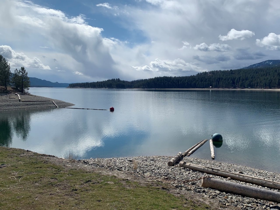 Fluffy white clouds overtop a reflective lake.