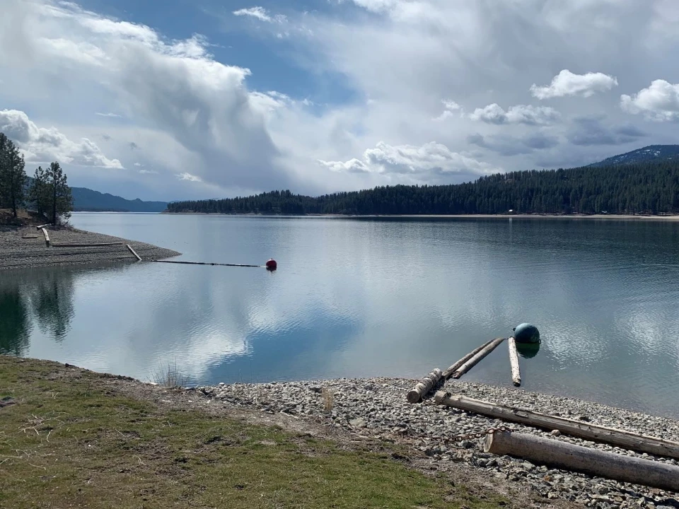 Fluffy white clouds overtop a reflective lake.