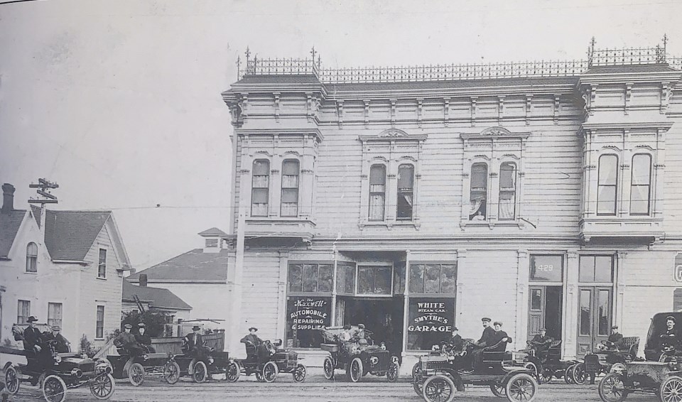 Old cars with men in front of building