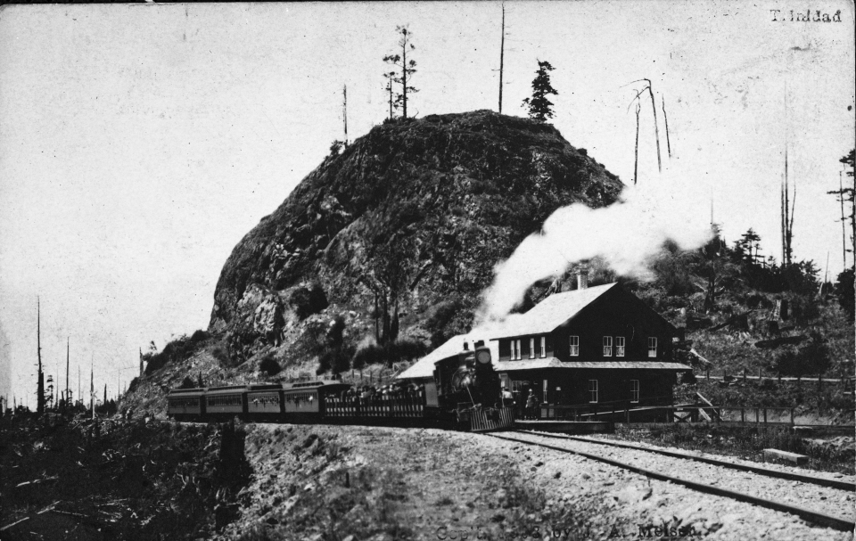 Train on tracks with hill behind and steam coming out