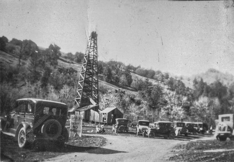 Old cars with oil derrick and hills